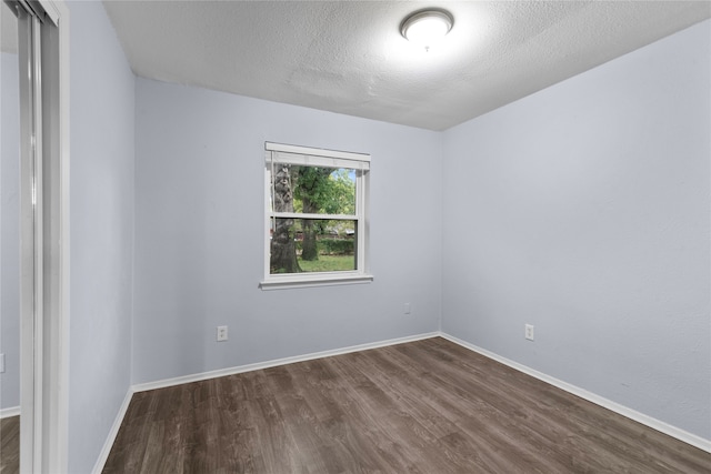 empty room featuring dark wood-type flooring and a textured ceiling