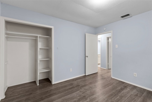 unfurnished bedroom with dark wood-type flooring and a textured ceiling