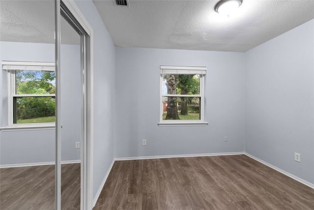 unfurnished bedroom with dark wood-type flooring, a textured ceiling, and a closet