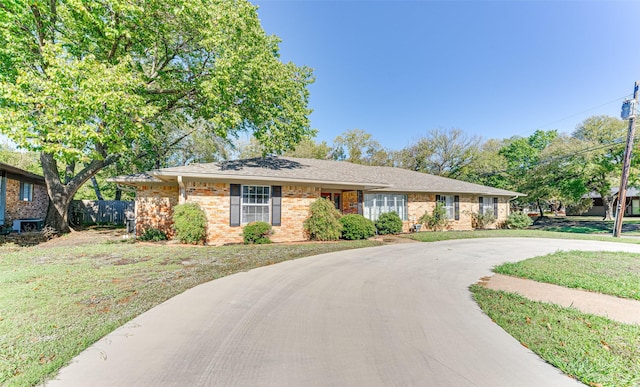 ranch-style home with driveway, a front yard, and brick siding