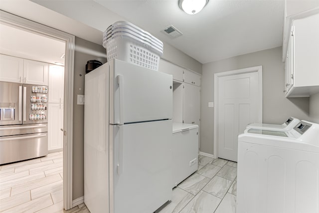 clothes washing area with cabinets and washer and dryer