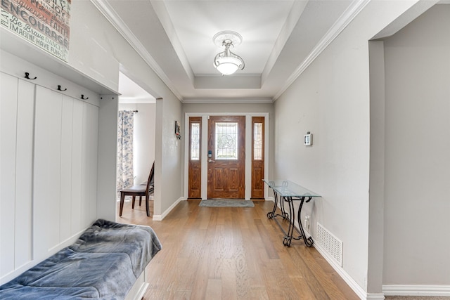 entryway with hardwood / wood-style flooring, ornamental molding, a raised ceiling, and a wealth of natural light