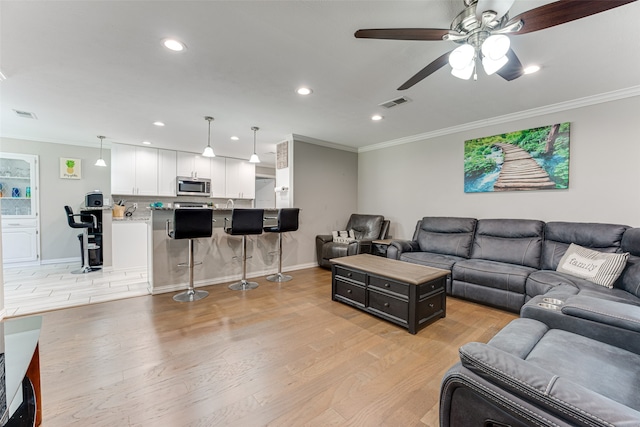 living room featuring crown molding, ceiling fan, and light hardwood / wood-style floors