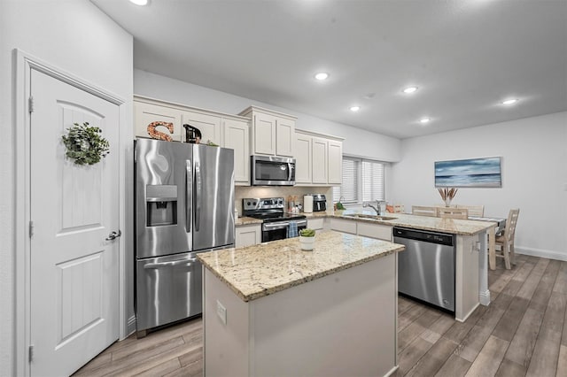 kitchen with stainless steel appliances, wood-type flooring, sink, and a center island