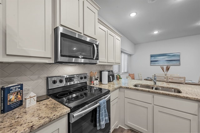 kitchen with white cabinets, stainless steel appliances, sink, and light stone countertops