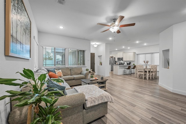 living room with light hardwood / wood-style floors and ceiling fan