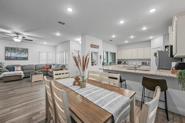 dining space with hardwood / wood-style floors, ceiling fan, and sink