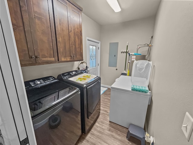 laundry area featuring separate washer and dryer, light hardwood / wood-style floors, electric panel, and cabinets