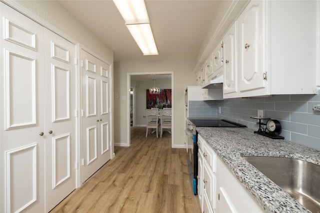 kitchen featuring tasteful backsplash, stainless steel electric range, white cabinetry, light stone countertops, and light hardwood / wood-style floors