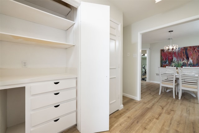 interior space with hanging light fixtures, light hardwood / wood-style floors, white cabinetry, and an inviting chandelier