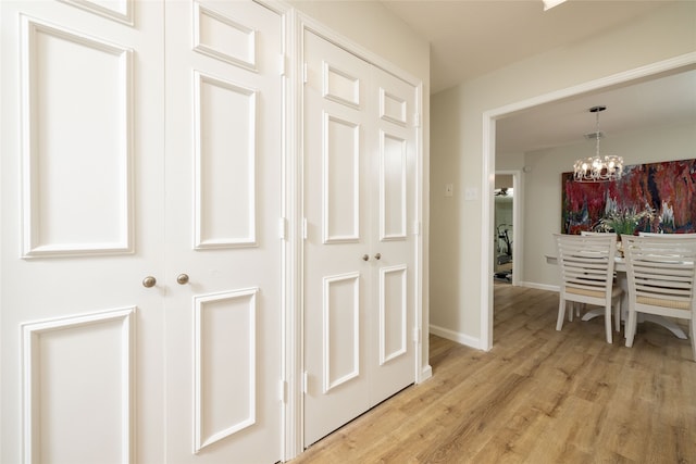 corridor with light hardwood / wood-style floors and a chandelier