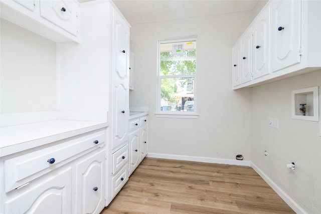 washroom featuring light wood-type flooring, hookup for a washing machine, and cabinets