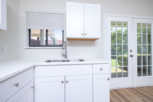 kitchen with white cabinets, light hardwood / wood-style floors, sink, and a wealth of natural light