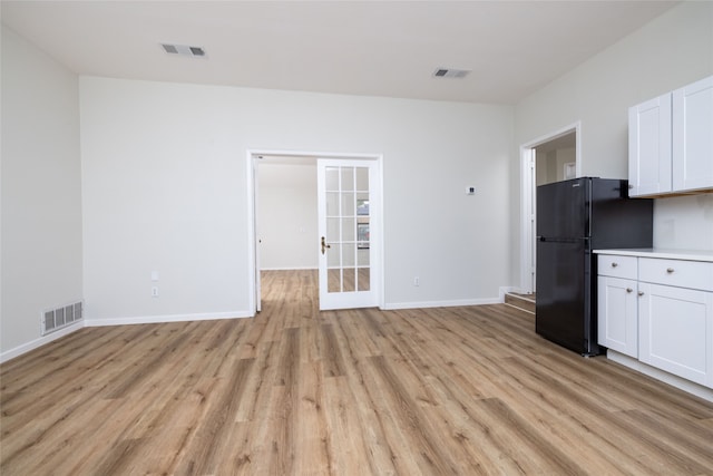 kitchen with light hardwood / wood-style floors, black refrigerator, white cabinetry, and french doors