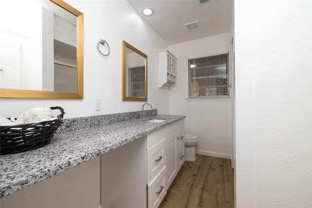 bathroom with wood-type flooring, toilet, and vanity