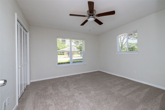 unfurnished bedroom with ceiling fan, multiple windows, and carpet flooring