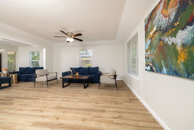 living area with a wealth of natural light, light hardwood / wood-style floors, and ceiling fan with notable chandelier