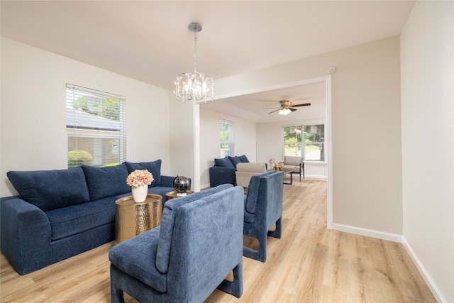 living room with ceiling fan with notable chandelier and light hardwood / wood-style flooring