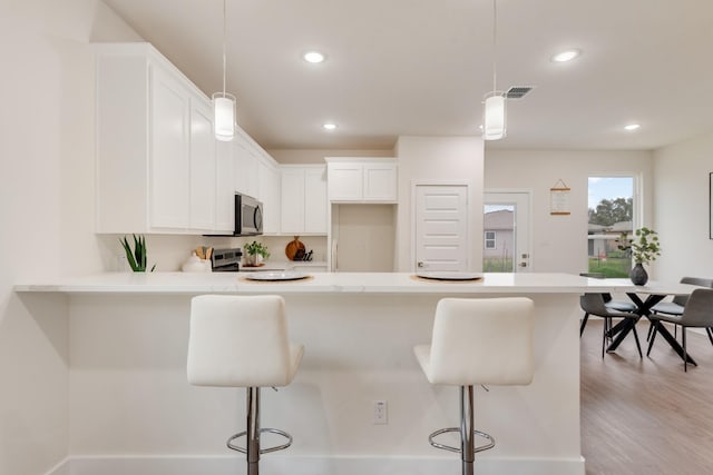 kitchen with light countertops, a breakfast bar, white cabinets, and stainless steel appliances