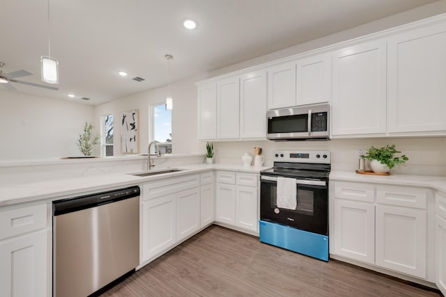 kitchen featuring hanging light fixtures, white cabinetry, stainless steel appliances, and a sink