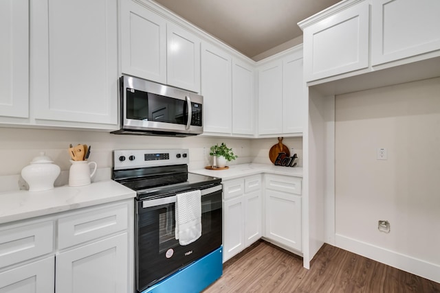 kitchen with light wood finished floors, appliances with stainless steel finishes, light stone countertops, and white cabinets