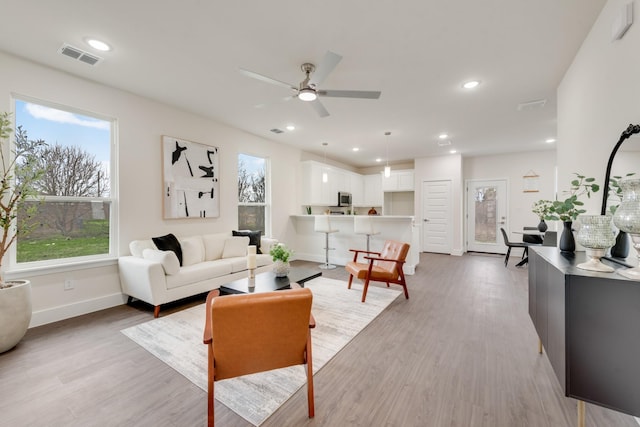 living area with light wood-style flooring, recessed lighting, visible vents, a ceiling fan, and baseboards