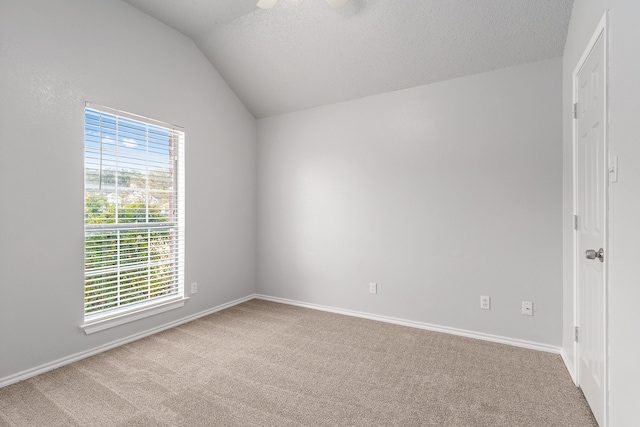 carpeted spare room featuring vaulted ceiling, ceiling fan, and a textured ceiling