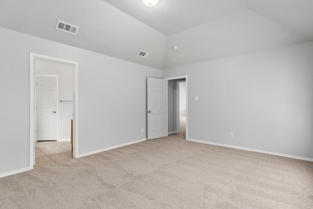 carpeted empty room with a textured ceiling and vaulted ceiling