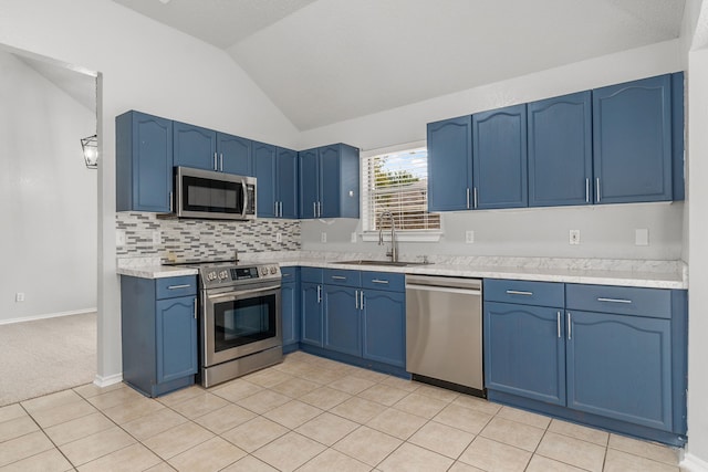 kitchen with light tile patterned flooring, appliances with stainless steel finishes, sink, vaulted ceiling, and blue cabinets