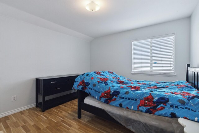 bedroom with wood-type flooring and vaulted ceiling