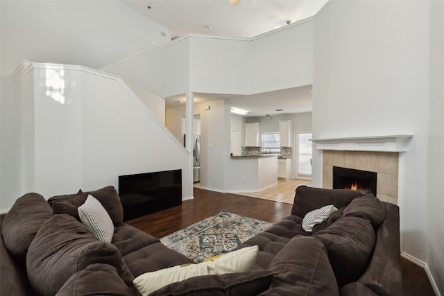 living room with light hardwood / wood-style floors, a tiled fireplace, and a towering ceiling