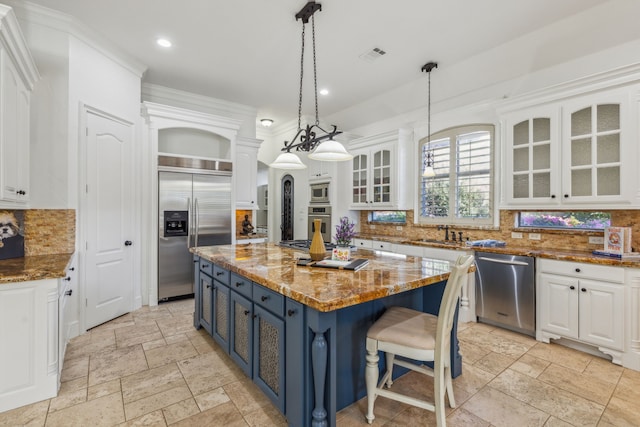 kitchen with a kitchen island, appliances with stainless steel finishes, light stone countertops, decorative backsplash, and blue cabinets