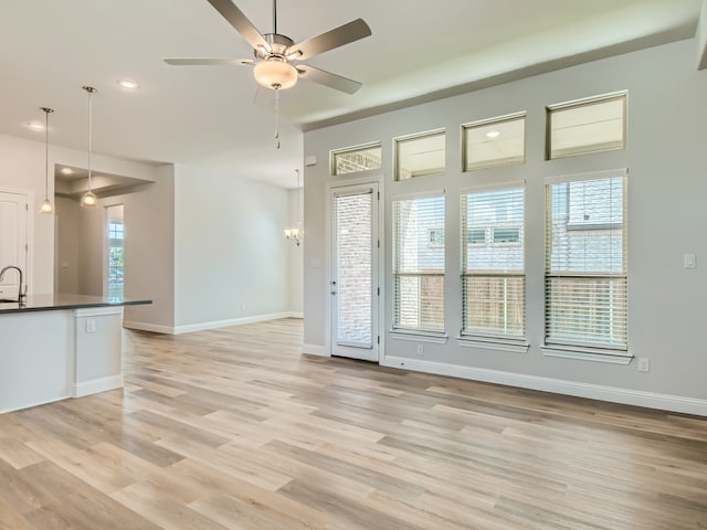 unfurnished living room featuring ceiling fan, a healthy amount of sunlight, sink, and light hardwood / wood-style flooring