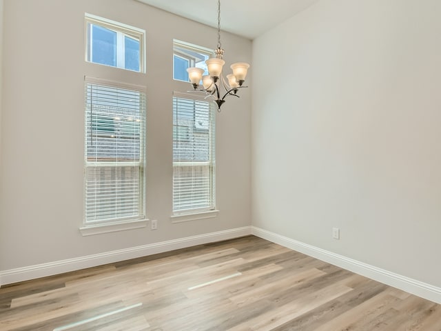 unfurnished dining area featuring an inviting chandelier and light hardwood / wood-style floors