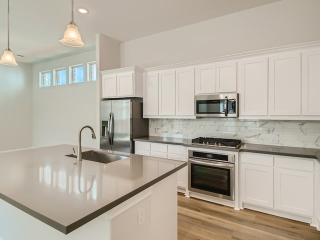 kitchen with stainless steel appliances, sink, decorative light fixtures, backsplash, and white cabinets