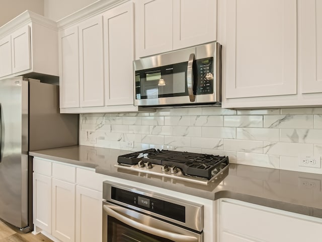 kitchen with tasteful backsplash, white cabinetry, appliances with stainless steel finishes, and light hardwood / wood-style floors