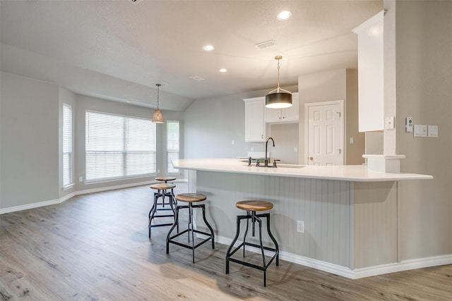 kitchen featuring white cabinetry, sink, light wood-type flooring, and kitchen peninsula