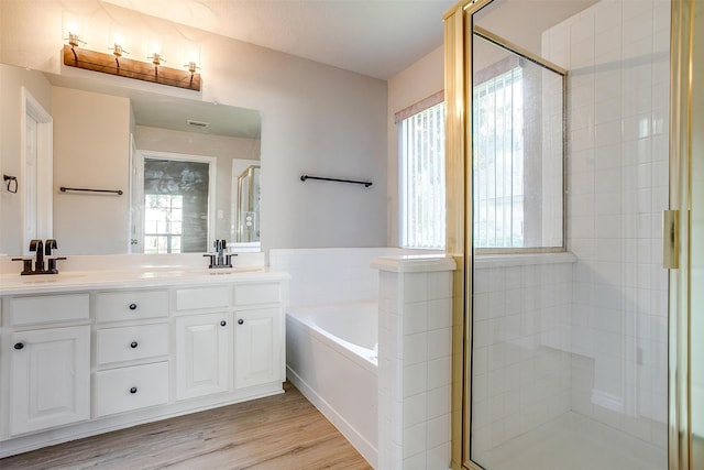 bathroom featuring plus walk in shower, vanity, and hardwood / wood-style floors