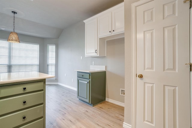 kitchen featuring white cabinets, hanging light fixtures, light hardwood / wood-style flooring, and vaulted ceiling