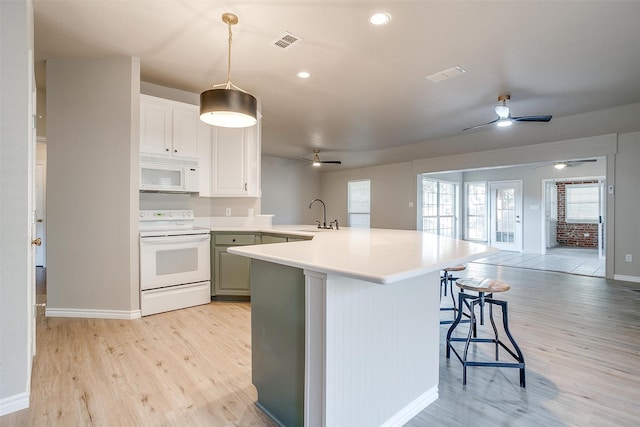 kitchen with light hardwood / wood-style floors, sink, a breakfast bar, pendant lighting, and white appliances