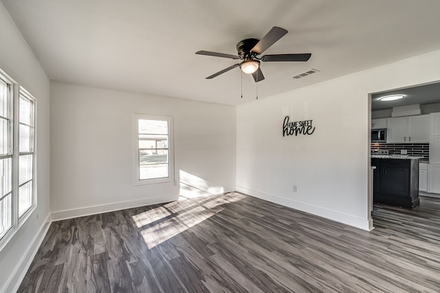 empty room with ceiling fan and dark hardwood / wood-style floors