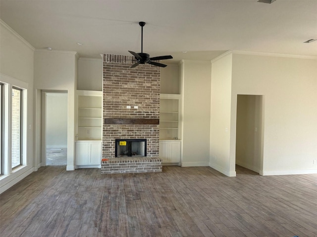 unfurnished living room featuring a brick fireplace, ornamental molding, and built in features