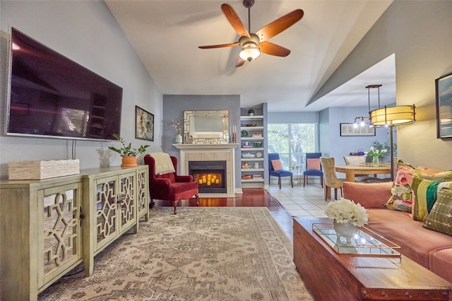 living room featuring ceiling fan, a tile fireplace, light wood-type flooring, and lofted ceiling