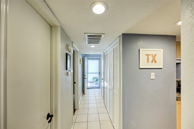 hallway featuring light tile patterned flooring and a textured ceiling