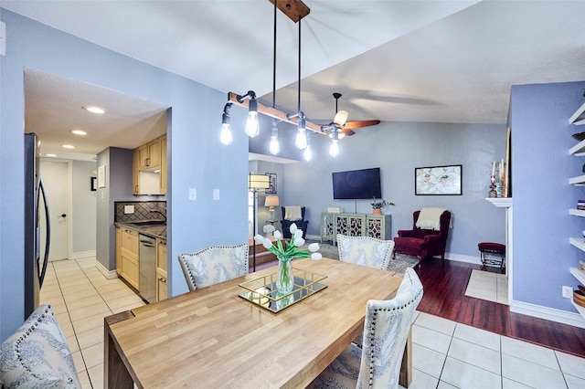 dining room with ceiling fan, sink, light hardwood / wood-style flooring, and vaulted ceiling