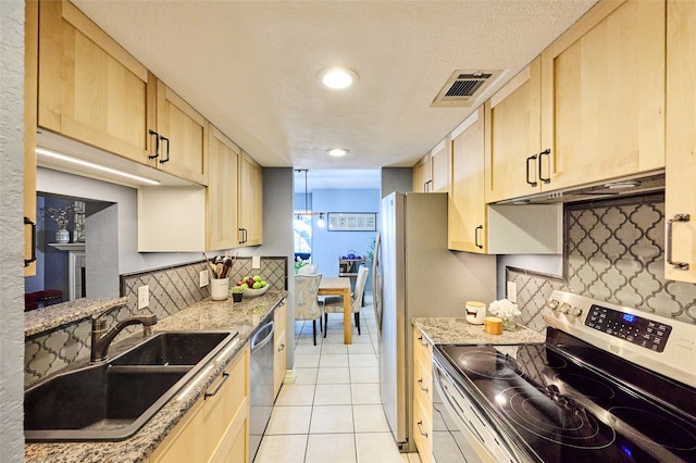 kitchen featuring sink, light tile patterned floors, light stone countertops, appliances with stainless steel finishes, and light brown cabinetry