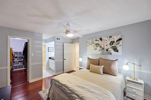 bedroom featuring a closet, a walk in closet, wood-type flooring, connected bathroom, and ceiling fan