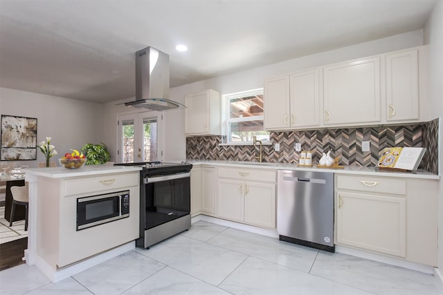 kitchen featuring kitchen peninsula, appliances with stainless steel finishes, tasteful backsplash, island range hood, and white cabinets