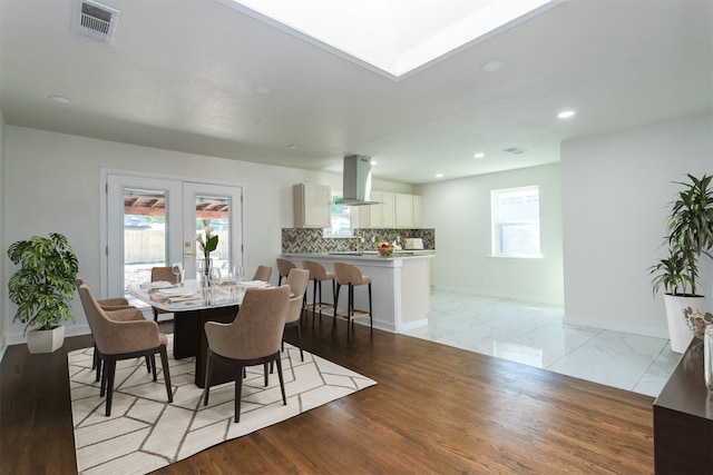 dining area featuring light wood-type flooring, french doors, and a healthy amount of sunlight