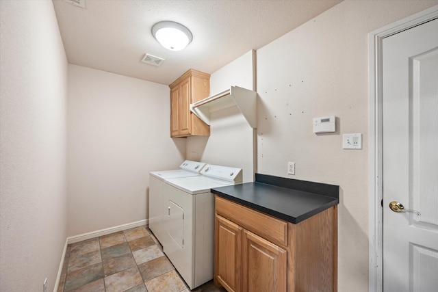 clothes washing area featuring a textured ceiling, cabinets, and washer and dryer